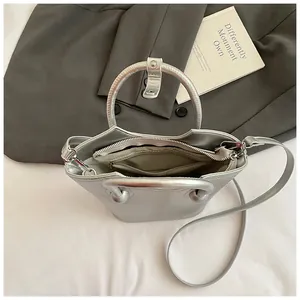 Silver metallic bucket bag with ring handle and interior pocket shown from a top view