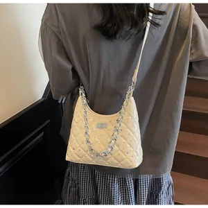Dettaglio borsa hobo trapuntata crema con borchie argentate e chiusura a girello in metallo