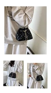 Quilted black bucket bag with silver studs and chain strap shown on a model