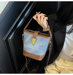 Dettaglio della borsa a secchiello in denim e pelle con fibbia dorata e tracolla