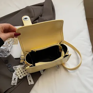 Borsa a mano in pelle giallo pallido con chiusura in metallo e charm di perle e pizzo