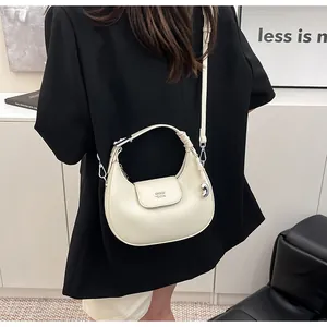 Vista dettagliata della borsa a mezzaluna bianco crema con logo argentato