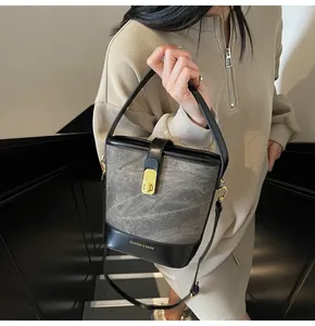 Dettaglio della borsa a secchiello in tela vintage con finiture in pelle nera