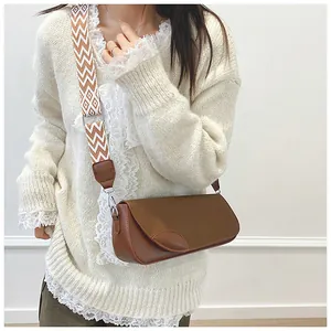 Close-up of brown crossbody bag with leaf leather accents and patterned wide strap