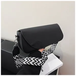Detail of minimalist black faux leather crossbody bag with wide geometric woven strap