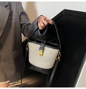 Dettaglio della borsa a secchiello bicolore con hardware dorato e tracolla regolabile