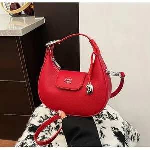 Dettaglio borsa in pelle rossa con logo COIH 2DN e ciondolo a cuore in argento