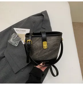 Dettaglio della borsa a secchiello grigia con chiusura a scatto dorata e tessuto testurizzato