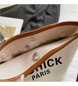 Detail view of canvas bucket bag with magnetic snap closure and leather trim detailing
