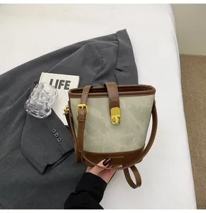 Dettaglio della chiusura dorata e rifiniture in pelle marrone su borsa a secchiello