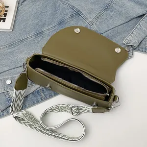 Olive green crossbody bag with patterned strap shown with denim and lifestyle props