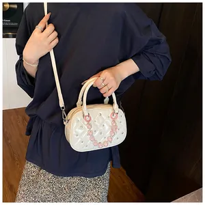 Close-up of quilted ivory bowling bag with pink crystal chain and rhinestone details