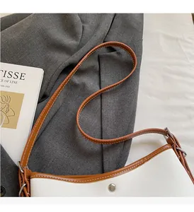 Detail of canvas bucket bag with brown leather trim and silver metal buckle hardware