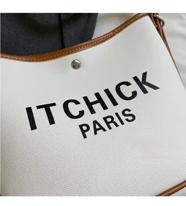 Close-up of canvas bucket bag with 'IT CHICK PARIS' print and silver metal button