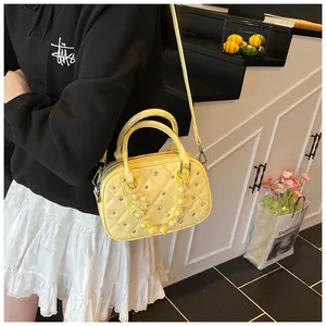 Detail of yellow quilted patent leather handbag with bead chain in a lifestyle setting