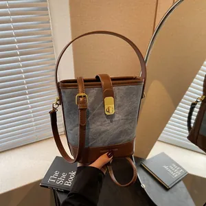 Borsa a secchiello alla moda con cuciture a contrasto in denim e pelle marrone con oro