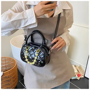 Detail of black quilted bowling bag with silver rivets and yellow butterfly chain