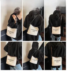 Detail view of the contrast trim and lettering on the canvas shoulder bucket bag