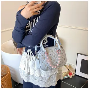 Close-up of quilted light blue handbag with silver studs and pink bead chain accessory