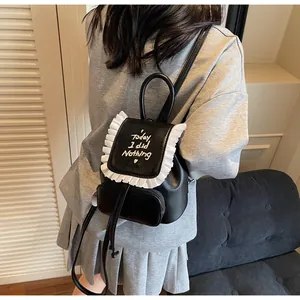 Détail de broderie et bordure à volants sur un mini sac à dos noir avec bretelles fines