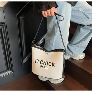 Detailed top view of contrast canvas tote bag with black leather trim and letter print