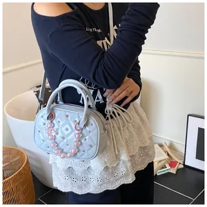 Close-up of quilted light blue bowling bag with silver studs and heart-shaped pendant