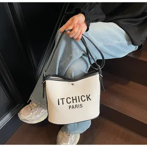 Detail of canvas bucket bag with black leather trim and ITCHICK PARIS lettering print