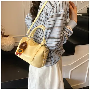 Detail of light yellow crocodile pattern bowling bag with cute doll charm and shoulder strap