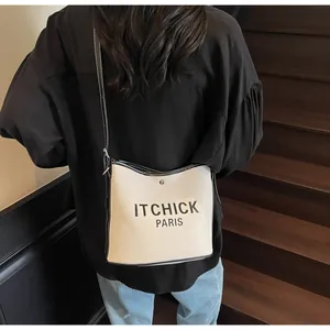 Detail of contrast stitch canvas bucket bag with letter print shown on a model
