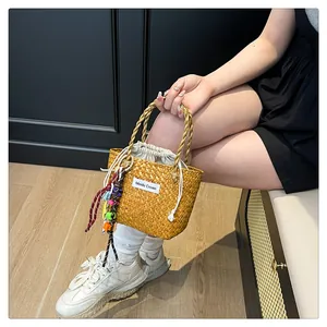 Detail of woven straw tote bag featuring a beige drawstring pouch and tassel charm