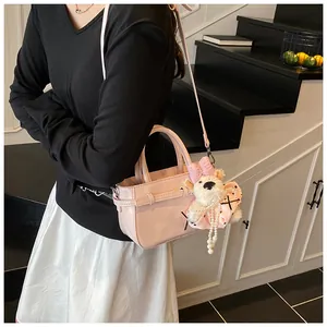 Détail du sac à main rose en PU avec breloque d'ours porté par un mannequin en intérieur