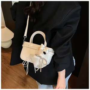 Détail d'un sac à main blanc avec breloque en peluche sur un blazer noir chic