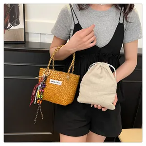 Detail of yellow woven straw bag with drawstring inner pouch and tassel charm