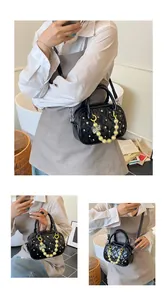 Detail of black quilted crossbody bag featuring white polka dots and beaded bow charm