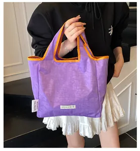 Detail of purple nylon tote bag with orange piping and brand tag for casual daily use