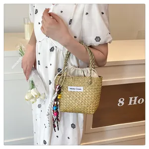 Detail of handwoven straw bag with drawstring liner and decorative beaded tassel pendant