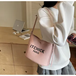 Detail of pink pebbled leather bucket bag with printed text and slim shoulder strap