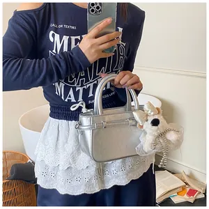 Détail du sac à main argenté métallisé avec boucle décorative et breloque ours en peluche