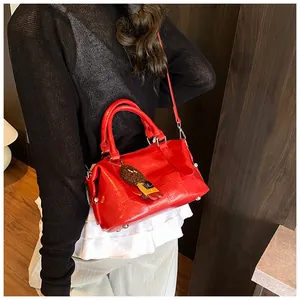 Detail of red crocodile embossed bowling bag with plush bear charm and long strap