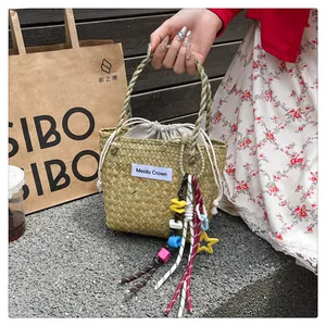 Detail of woven straw tote bag with drawstring lining and colorful beaded star charm