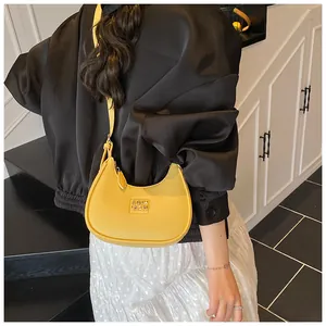 Detail of a bright yellow crescent bag with lychee texture leather and metal logo plaque