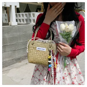 Detail of woven straw handbag with colorful acrylic charms and drawstring closure