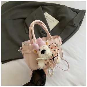 Détail d'un sac à main rose en similicuir avec charm ours en peluche et foulard en soie