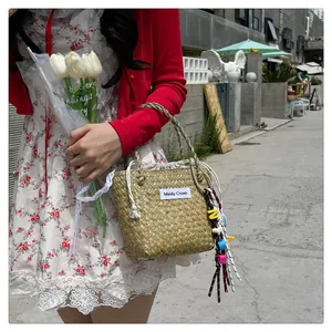Detail of woven straw bag with drawstring lining and colorful tassel charm