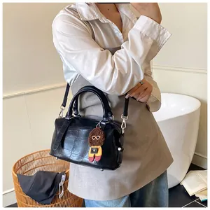 Close-up of black crocodile pattern Boston bag with cute brown puppy charm on the side