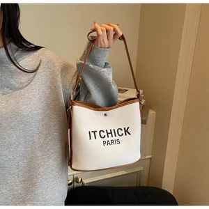Close-up of contrast stitching and black letter printing on canvas bucket bag