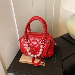 Red quilted leather bowling bag with studs and a pearl bow charm on a black display box