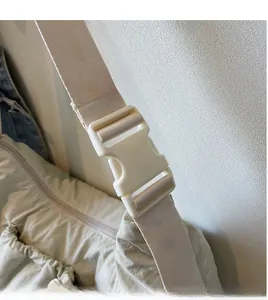 Dettaglio della tracolla regolabile in nylon e della fibbia della borsa beige casual