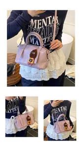 Detail view of purple faux-crocodile Boston bag with doll charm and shoulder strap
