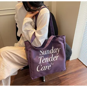 Dettaglio della borsa tote in tela viola con testo e tracolla regolabile resistente